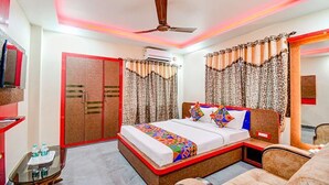 A hotel room with a bed, a TV, a wardrobe, and a ceiling fan. - FabHotel The Crown Comforts (Bidhannagar)