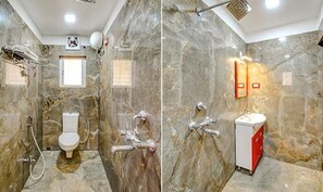 Une salle de bain avec un mur en marbre, des toilettes, une douche et un lavabo avec un meuble rouge.