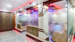 A modern hotel lobby with a clock, a patterned wall, and a glass partition. - FabHotel The Crown Comforts (Bidhannagar)