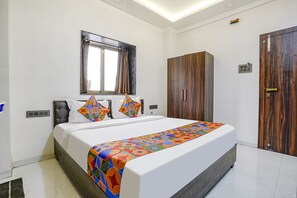 A neatly arranged bedroom with a bed, a wardrobe, and a window with curtains. - Fabhotel The Regal Inn (Nashik)