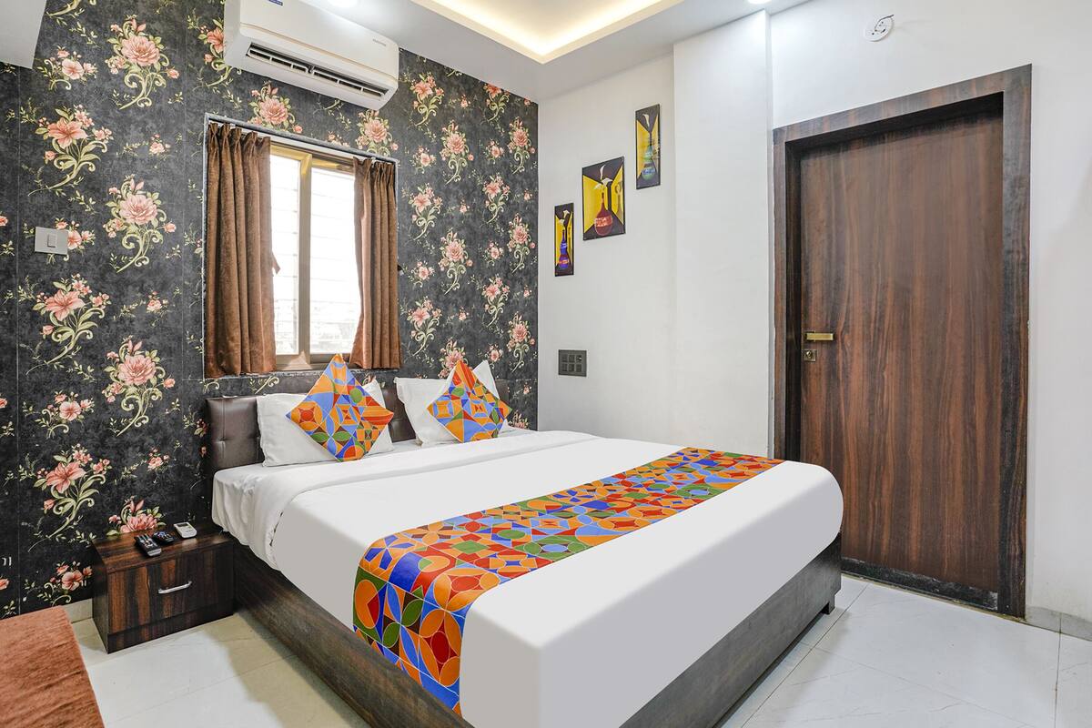 A neatly arranged bedroom with a bed, a nightstand, a window with curtains, and a door.