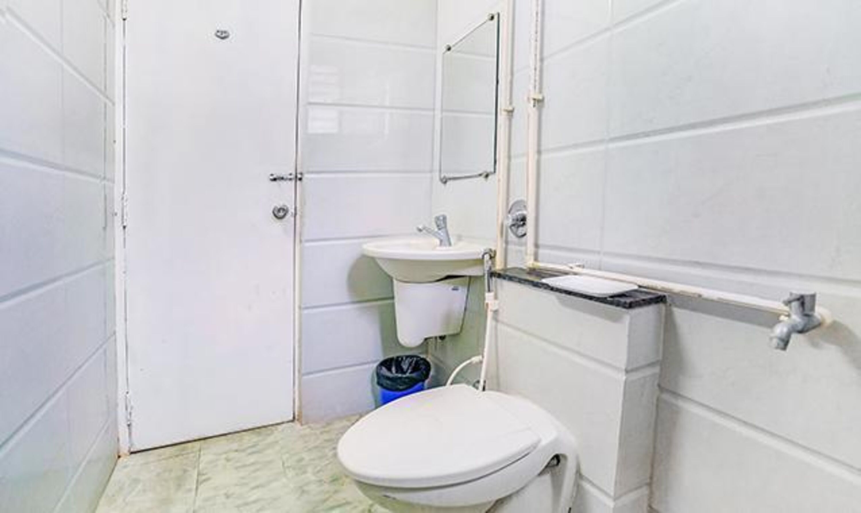 A small, basic bathroom with a toilet, sink, and mirror.