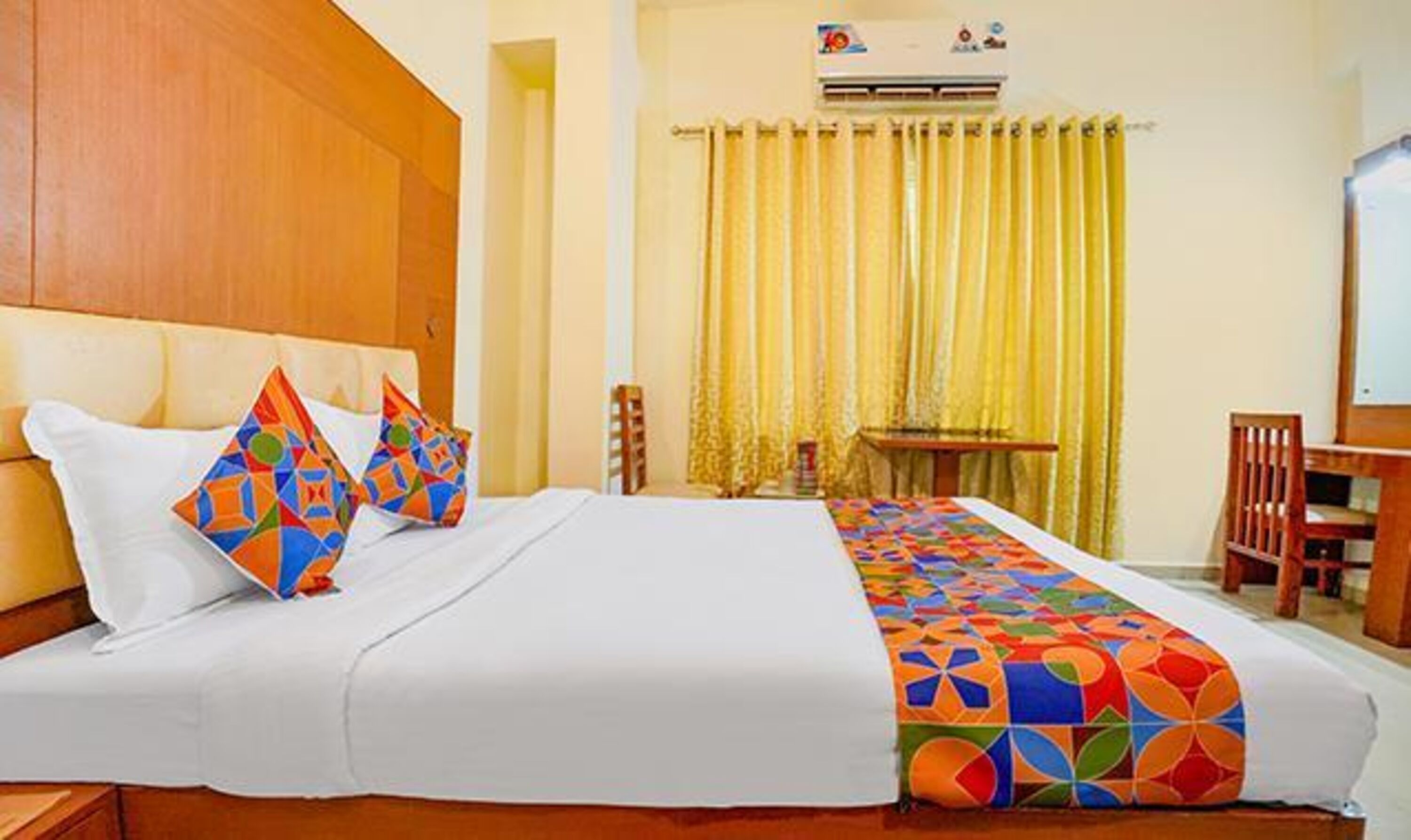 A hotel room with a large bed, a wooden headboard, a desk, and a chair.