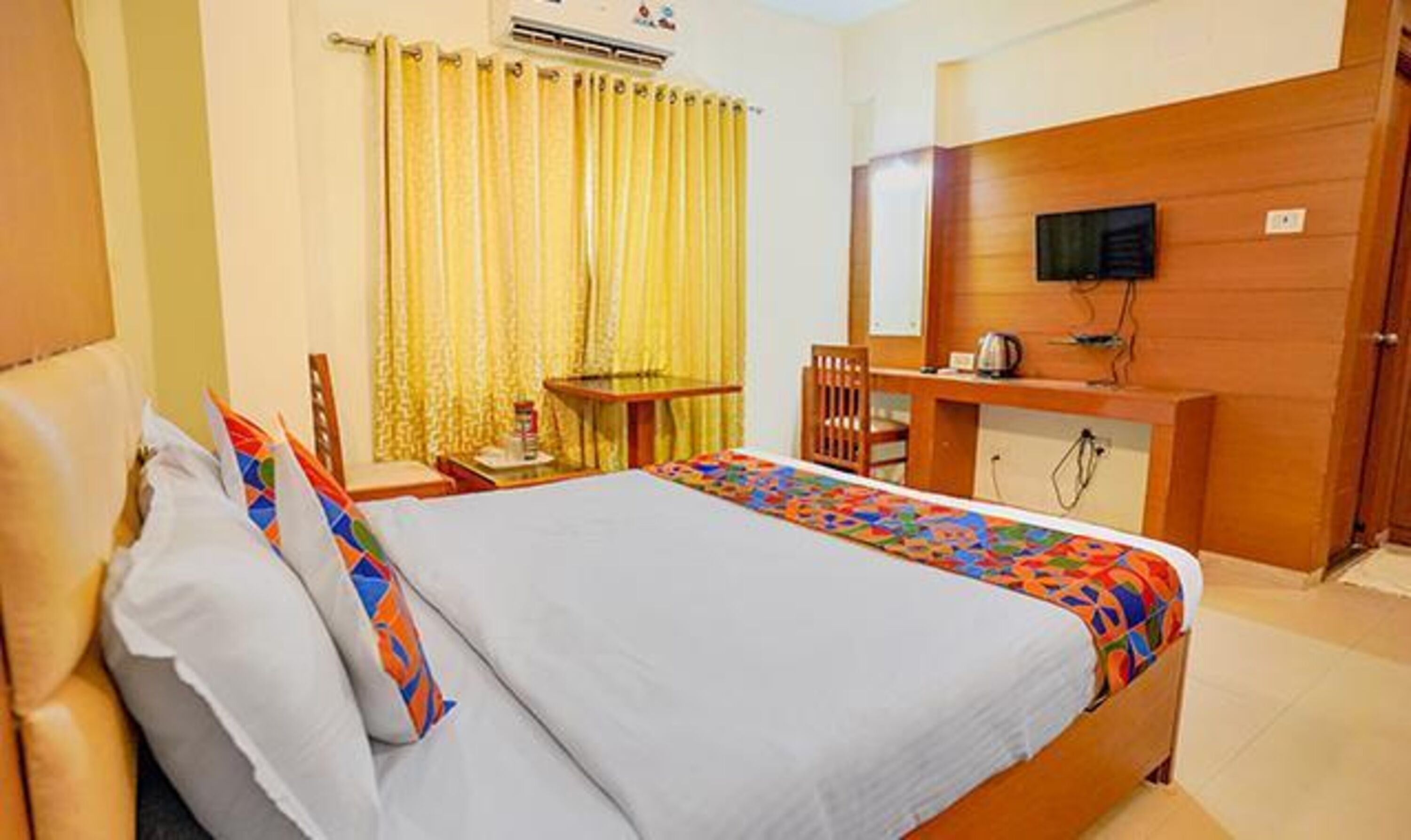 Ein Hotelzimmer mit Bett, Schreibtisch, Stuhl und Fernseher an der Wand.