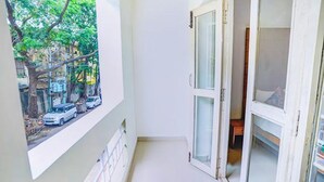 Ein schmaler Balkon mit Blick auf parkende Autos und Bäume.