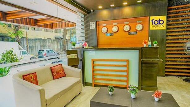 Ein Hotel-Rezeptionsbereich mit einer Couch, einem Empfangstresen und einer Wanduhr.
