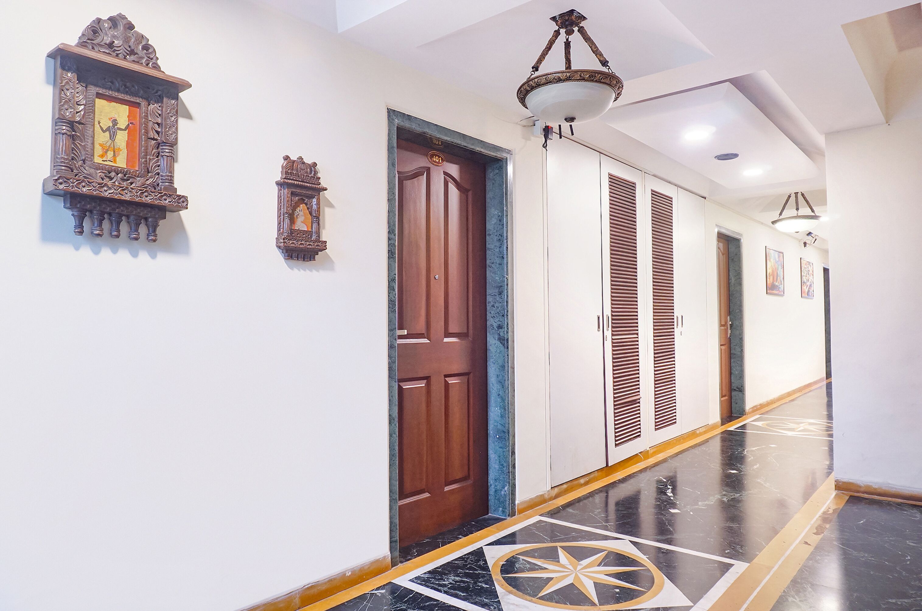 A hallway with a wooden door, a wall-mounted clock, and a ceiling light fixture.