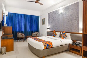 Une chambre d’hôtel équipée d’un lit, d’un bureau, d’une chaise, d’un téléphone et d’un ventilateur de plafond.