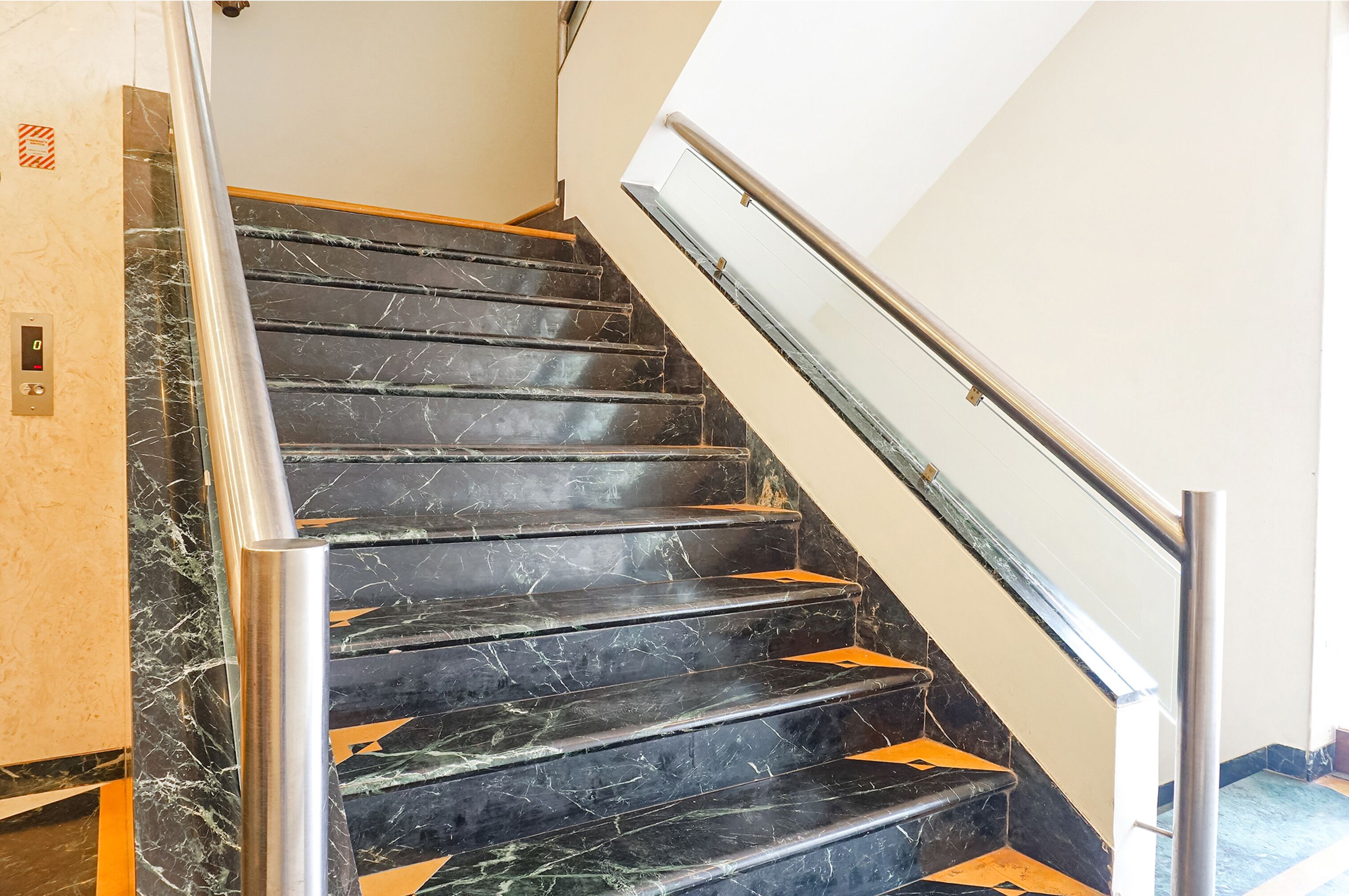 Una escalera con escalones de mármol negro y barandillas de metal.
