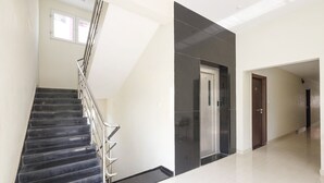 A modern interior with a staircase, a door, and a hallway. - Fabhotel Karthikeya Residency (Tirupati)