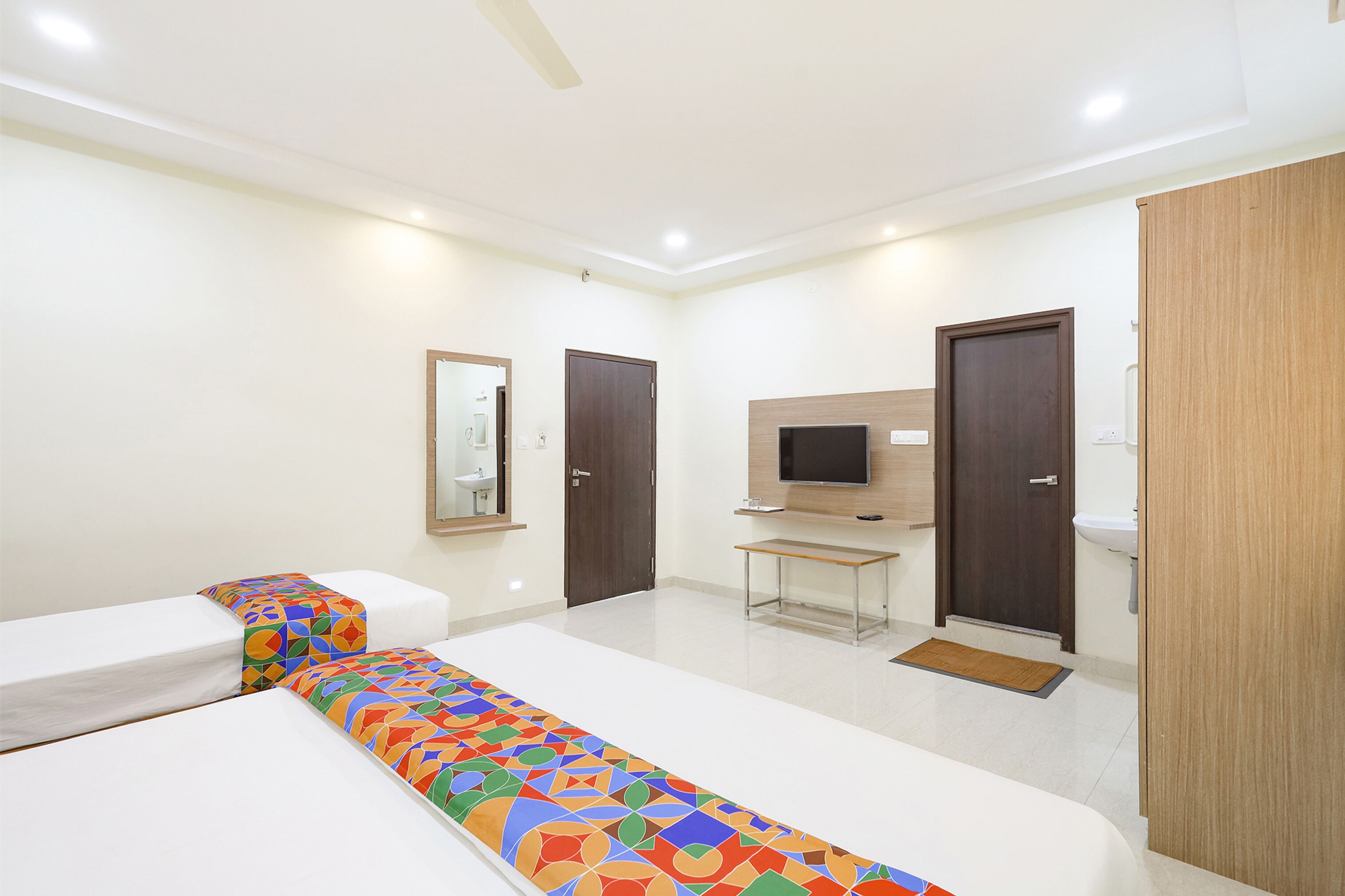 A hotel room with two beds, a TV, a desk, and a bathroom.