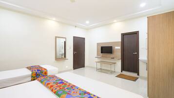 A hotel room with two beds, a TV, a desk, and a bathroom.