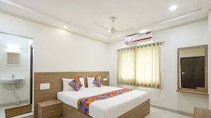 A modern hotel room with a large bed, bedside table, built-in wardrobe, and a small desk. - Fabhotel Karthikeya Residency (Tirupati)
