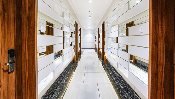 Um corredor de hotel com armários espelhados, painéis de madeira e chão de mármore.