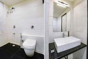 A bathroom with a white toilet, a shower, and a sink with a mirror above it. - Fabhotel The Nashik Inn (Nashik)