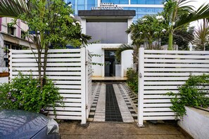 A hotel entrance with a gated driveway, a tiled pathway, and lush greenery. - Fabhotel The Nashik Inn (Nashik)