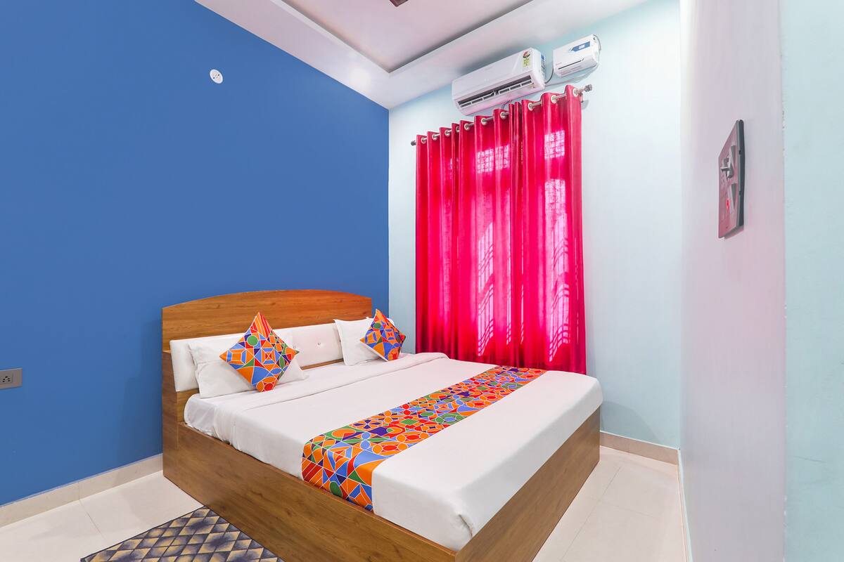 Um quarto com cama de madeira, roupa de cama branca e manta colorida com padrão geométrico.