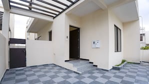 Entrada de un edificio con suelo a cuadros, una puerta y un pequeño espacio exterior con escalones.
