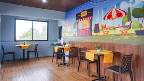 A restaurant with wooden flooring, tables with yellow tablecloths, and chairs. - Fabhotel Everest Inn (Pune)