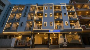 Een meerlaags hotel met een moderne gevel, meerdere balkons en een bord waarop staat dat het een Fab Hotels eigendom is.