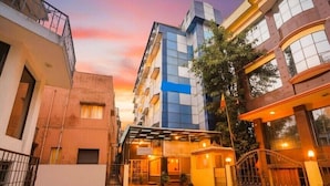 Un hotel con entrada cubierta, camino de acceso cerrado y una combinación de arquitectura moderna y tradicional.