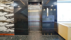 Un ascensor moderno con detalles metálicos y un panel de control en la pared.