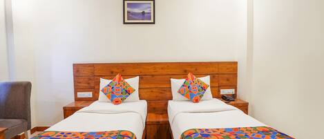 A hotel room with two beds, a wooden headboard, a framed picture on the wall, and a chair.