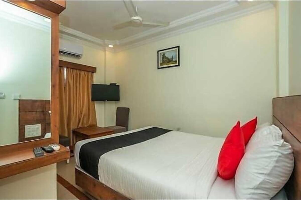 A hotel room with a bed, a bedside table, a chair, a TV, and a ceiling fan.