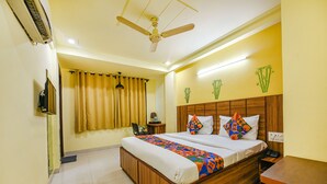 A hotel room with a wooden bed, a ceiling fan, a TV, and a small table. - Fabhotel Ishtara Auberge (New Delhi)