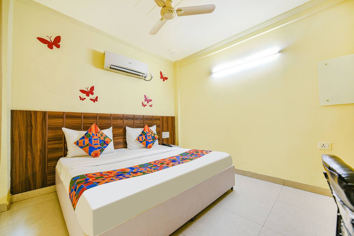 A hotel room with a bed, a ceiling fan, an air conditioner, and butterfly wall decals.