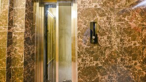 An elevator with marble walls and a metallic interior. - Fabhotel Ishtara Auberge (New Delhi)