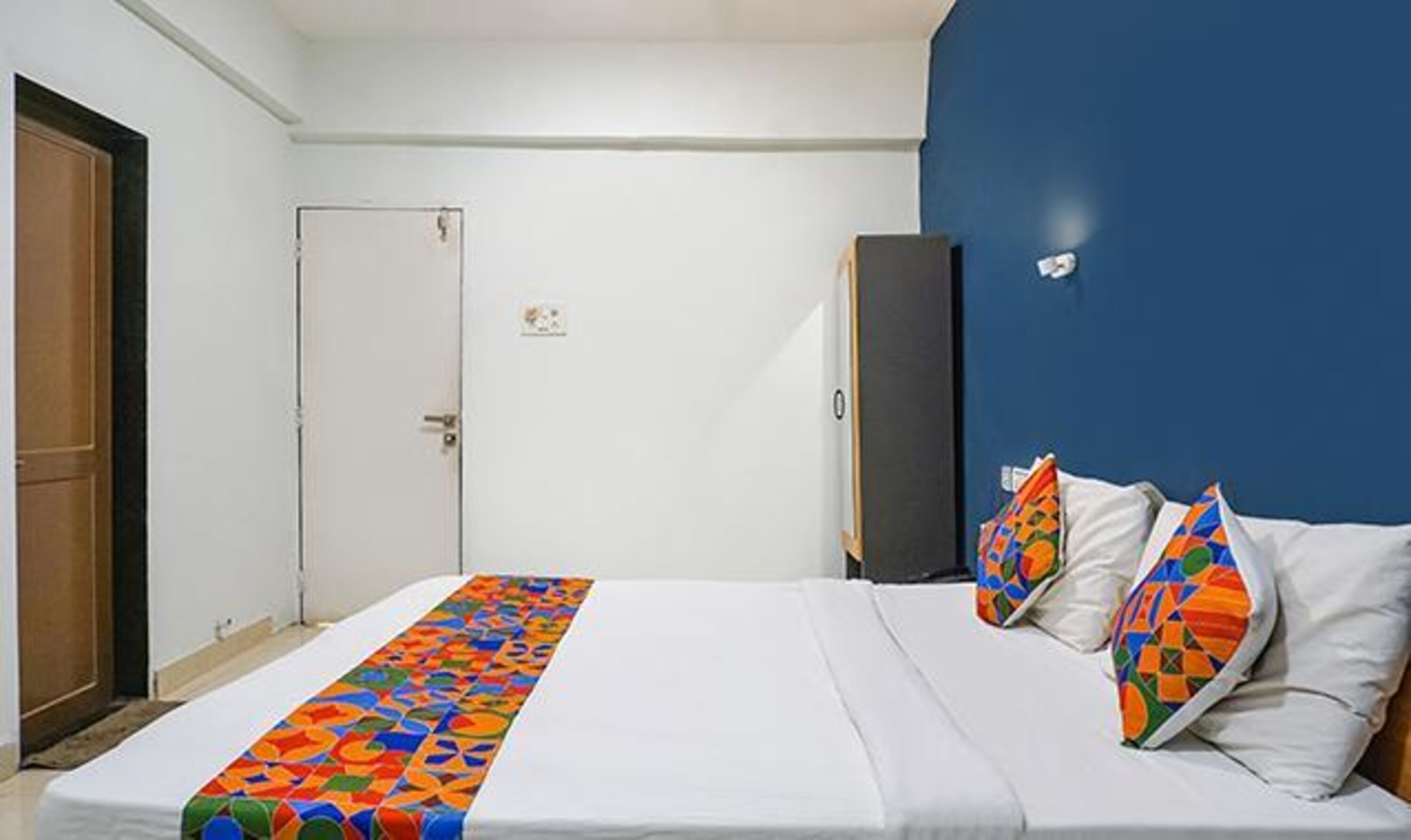 Habitación de hotel con cama, puerta, armario y pared azul.
