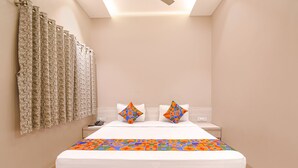 Una cama bien hecha con un edredón colorido, dos almohadas y una mesita de noche con un teléfono.