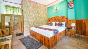 A bedroom with a wooden bed, a nightstand, a mirror, a wardrobe, and a green wall. - Fabhotel Hadimba Heights (Manali)