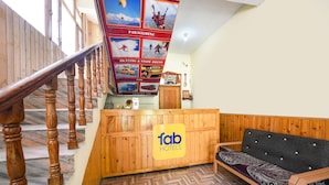 A reception area with a wooden desk, a sofa, and a staircase. - Fabhotel Hadimba Heights (Manali)