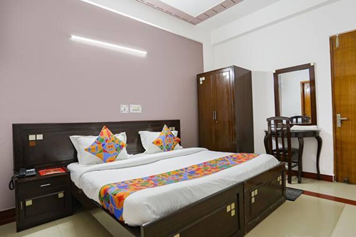 Quarto com cama, mesa de cabeceira, guarda-roupa e espelho.