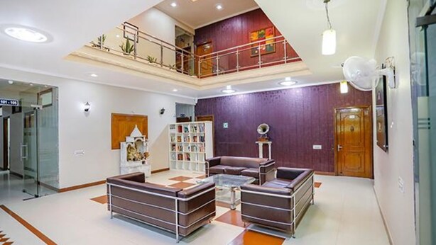 Un'ampia hall con soffitto alto, una scalinata, una reception e un'area relax con una libreria.