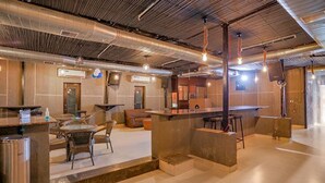 Zona bar moderna con posti a sedere, un bancone e condotte a vista sul soffitto.