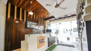A reception area with a wooden wall, a reception desk, and a ceiling fan. - Fabhotel Savera Park (Amritsar)