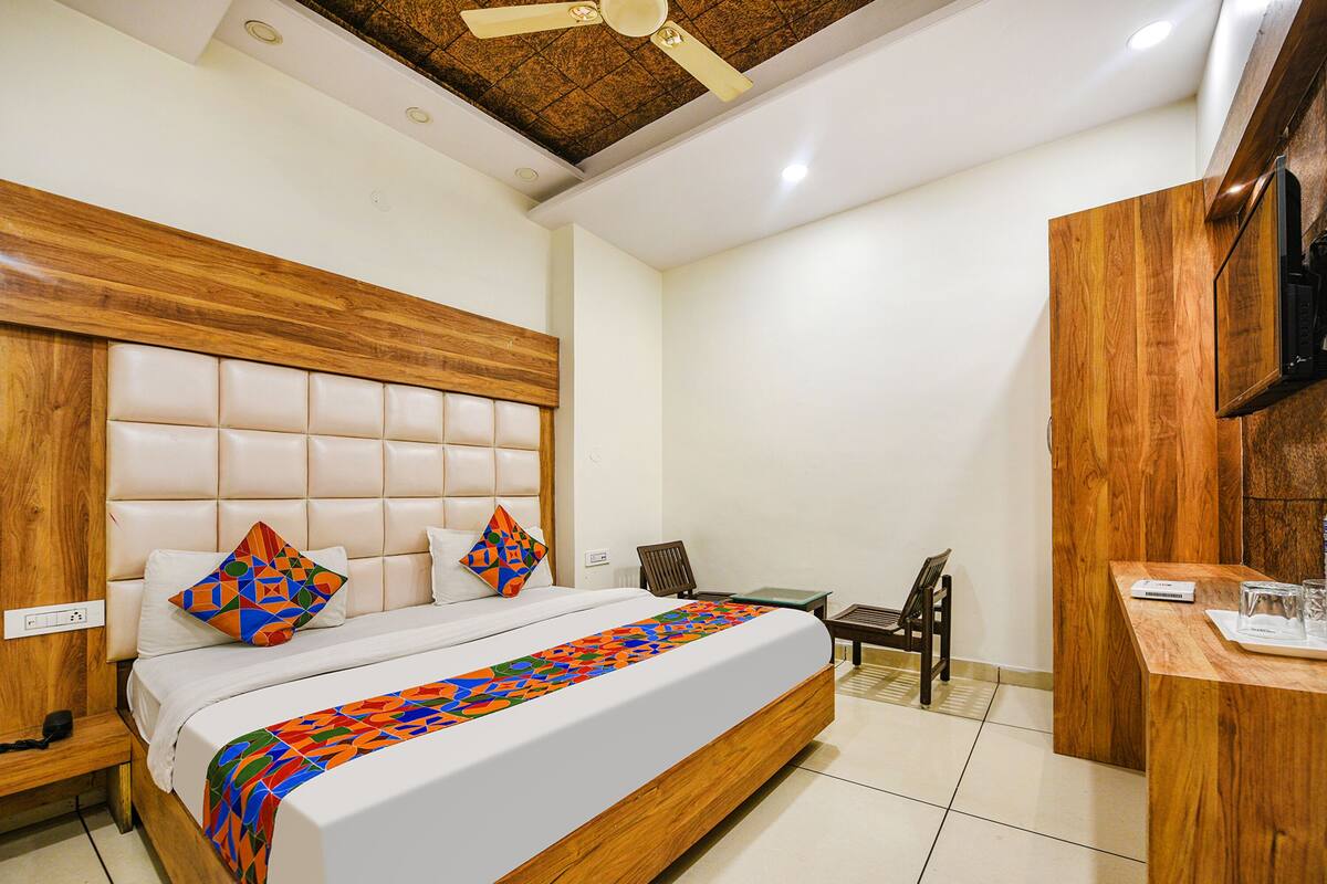 A hotel room with a large bed, wooden headboard, a desk, and a ceiling fan.