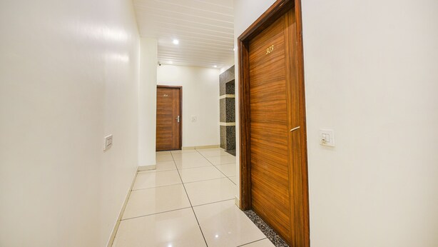 A hallway with a wooden door, a tiled floor, and a ceiling with recessed lighting. - Fabhotel Savera Park (Amritsar)