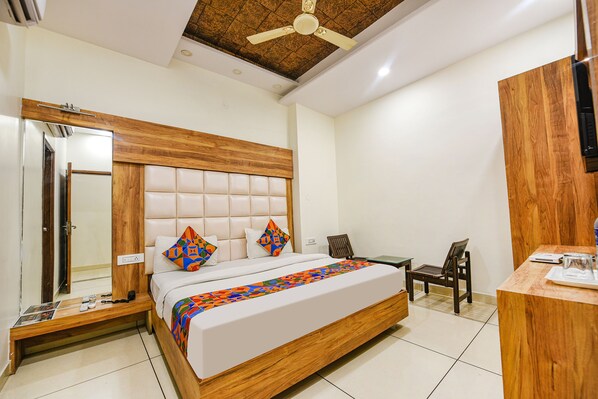 A bedroom with a wooden headboard, a bed with colorful pillows, a desk, and a chair.