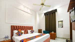 Een hotelkamer met een groot bed, een plafondventilator, een houten nachtkastje, een klein tafeltje en een spiegel aan de muur.