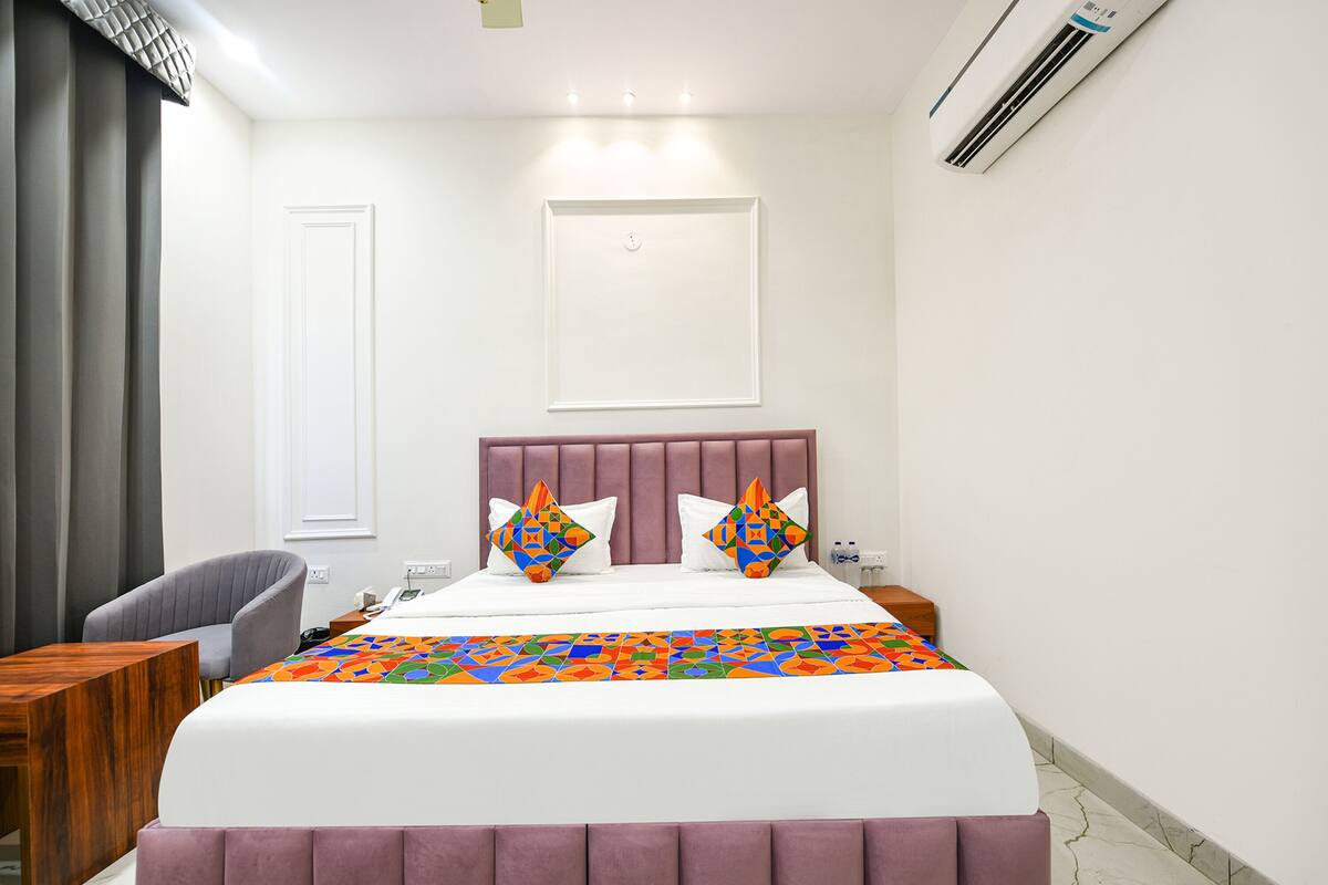 Een hotelkamer met een bed, een stoel, een nachtkastje en een airconditioning.