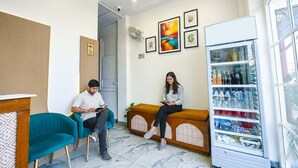 Een wachtruimte met blauwgroene stoelen, een houten bank en een automaat voor drankjes.