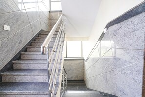 Eine Marmortreppe mit Metallgeländern, die zu einer Zwischenebene führt.