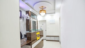 Un comptoir d’accueil orné d’une enseigne « Fab Hotels », une cloison en verre et un lustre moderne.