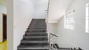 A staircase with black steps and metal handrails, leading to a landing with a window.