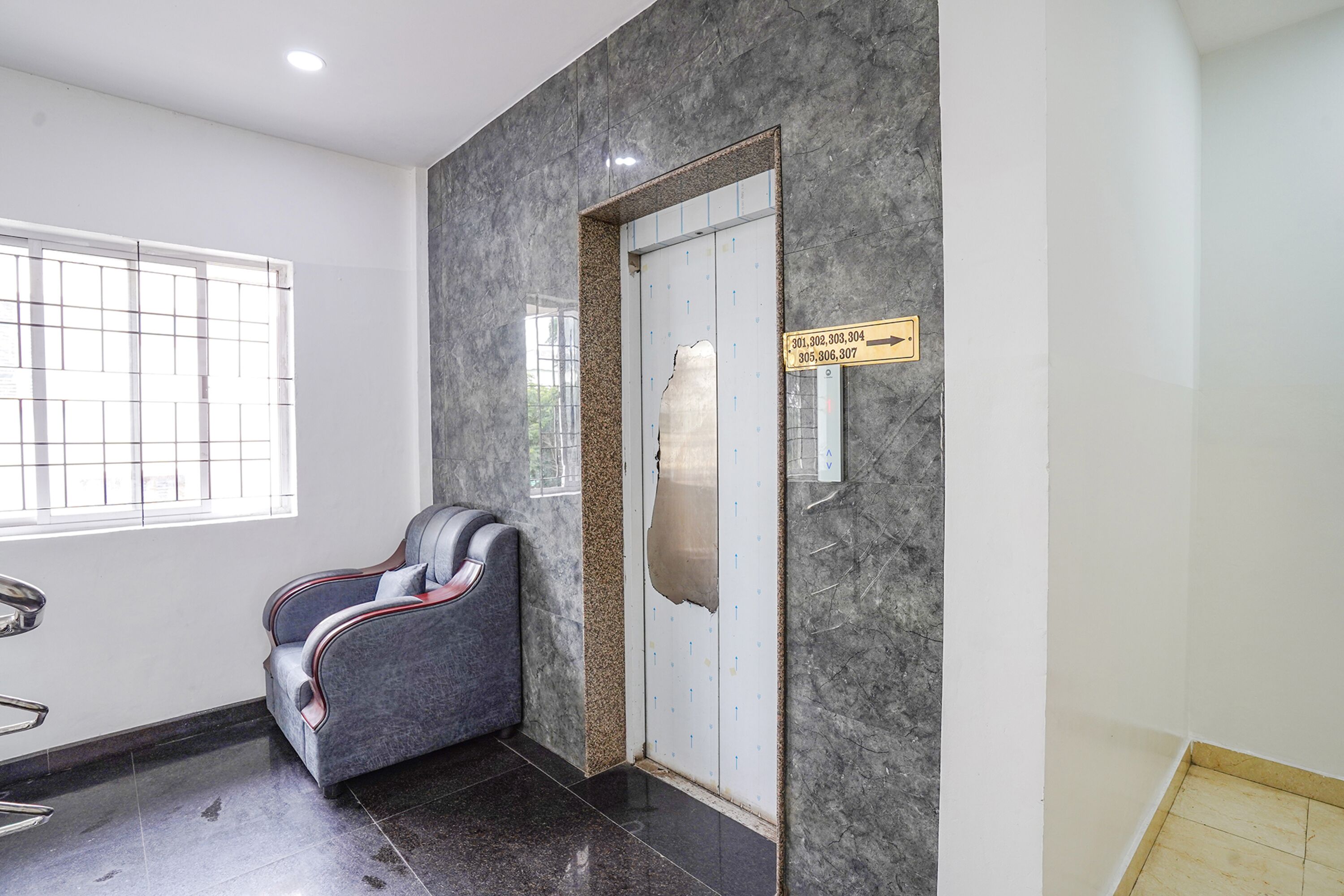 A waiting area with a massage chair, a reception desk, and a sign indicating directions.