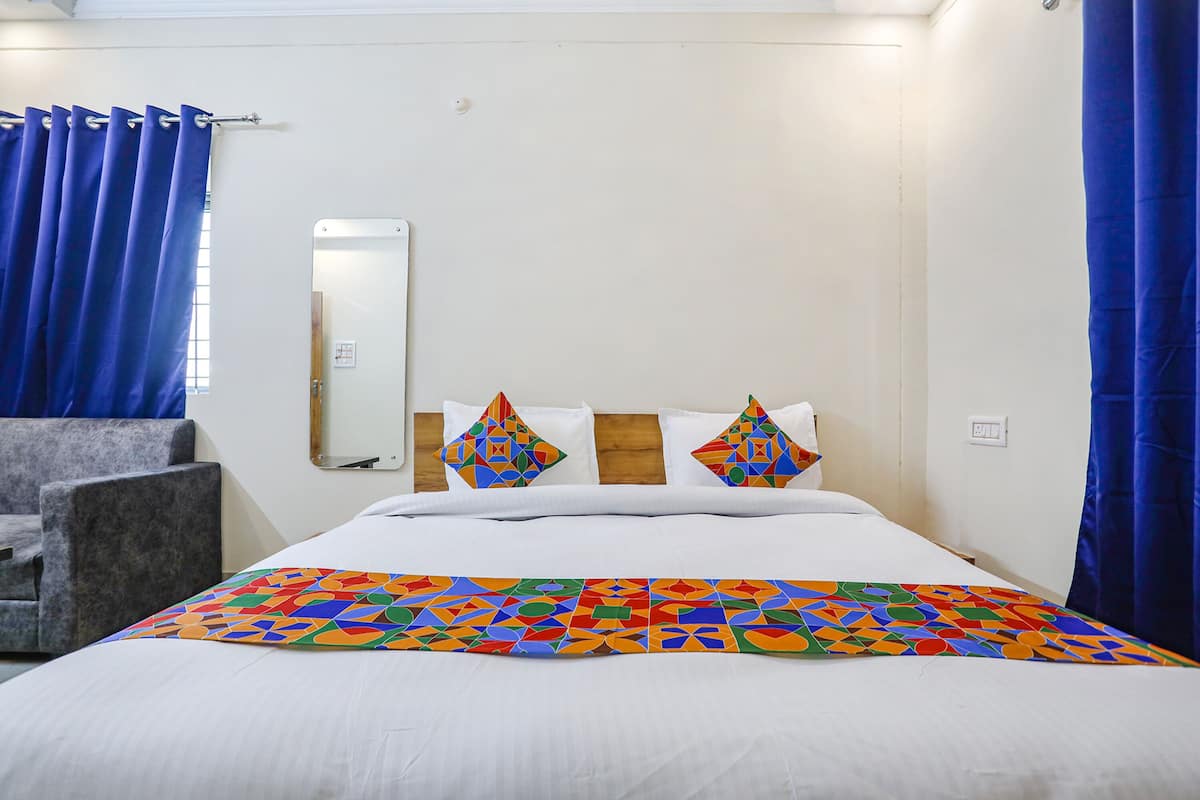 Una habitación de hotel con una cama, una silla, un espejo y cortinas azules.